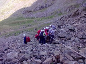 The stretcher being carried down the scree with the safety of a backrope